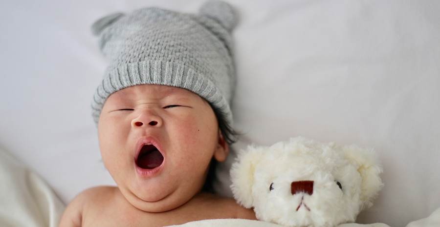 Baby with knit hat on yawning