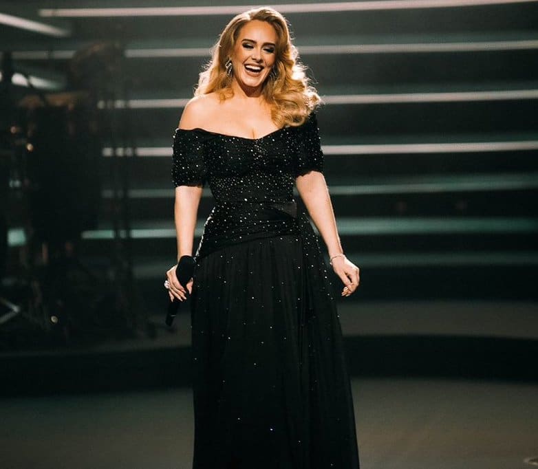 Singer Adele in black gown on stage with microphone