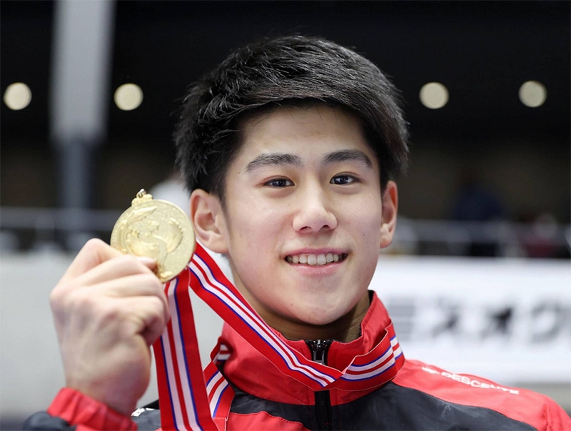 Smiling Japanese man holding his gold medal