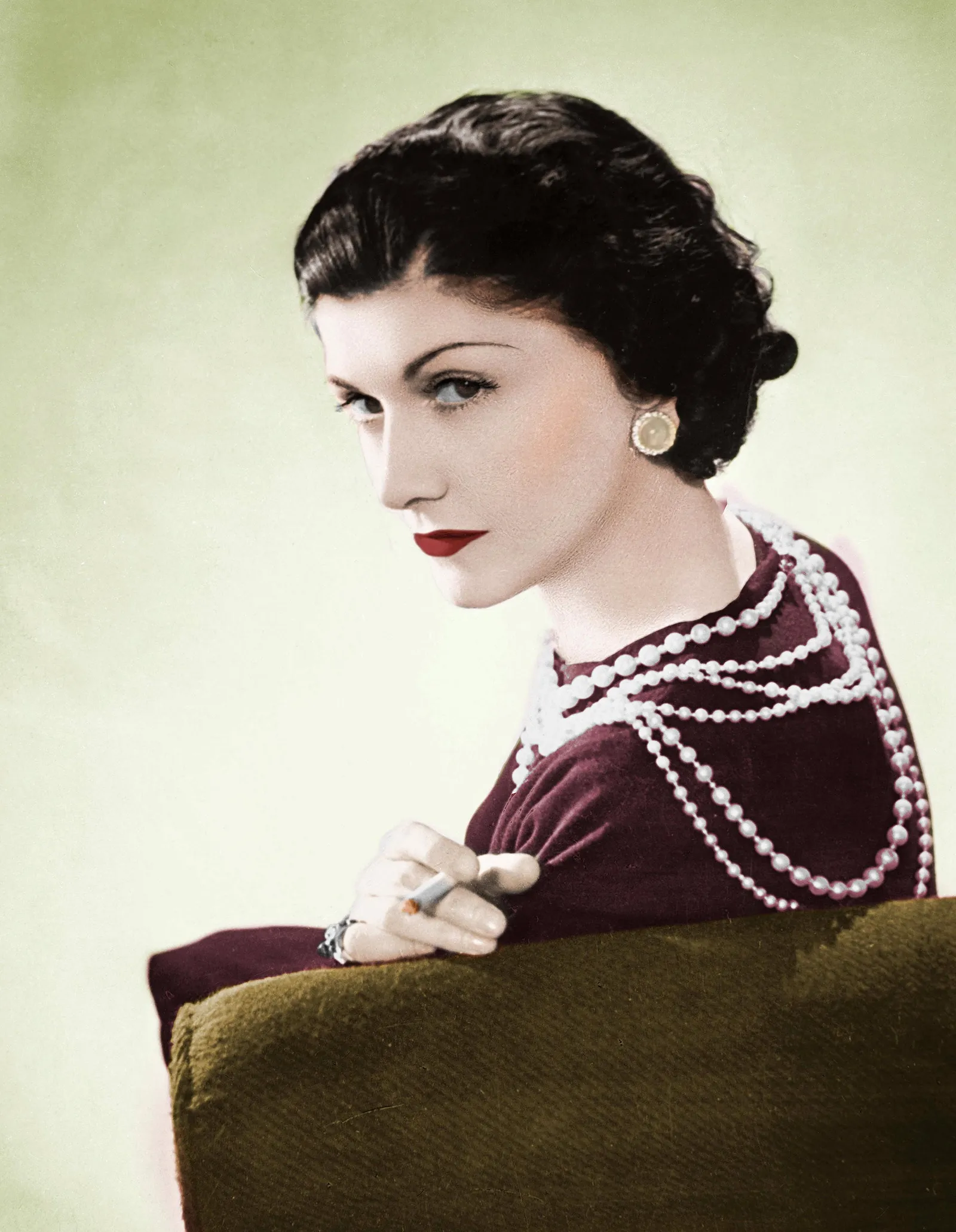 Old colorized photo of fashion designer coco chanel looking over shoulder