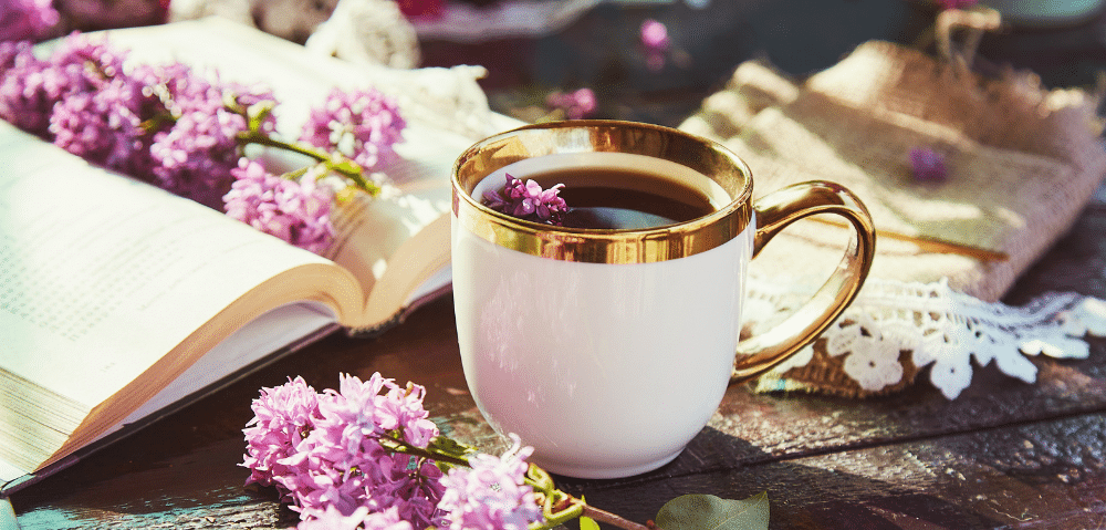 cup of coffee among books and flowers