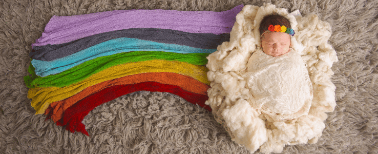 baby sleeping, lying on a rainbow rug