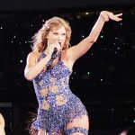 Taylor Swift on stage dancing and singing in purple outfit